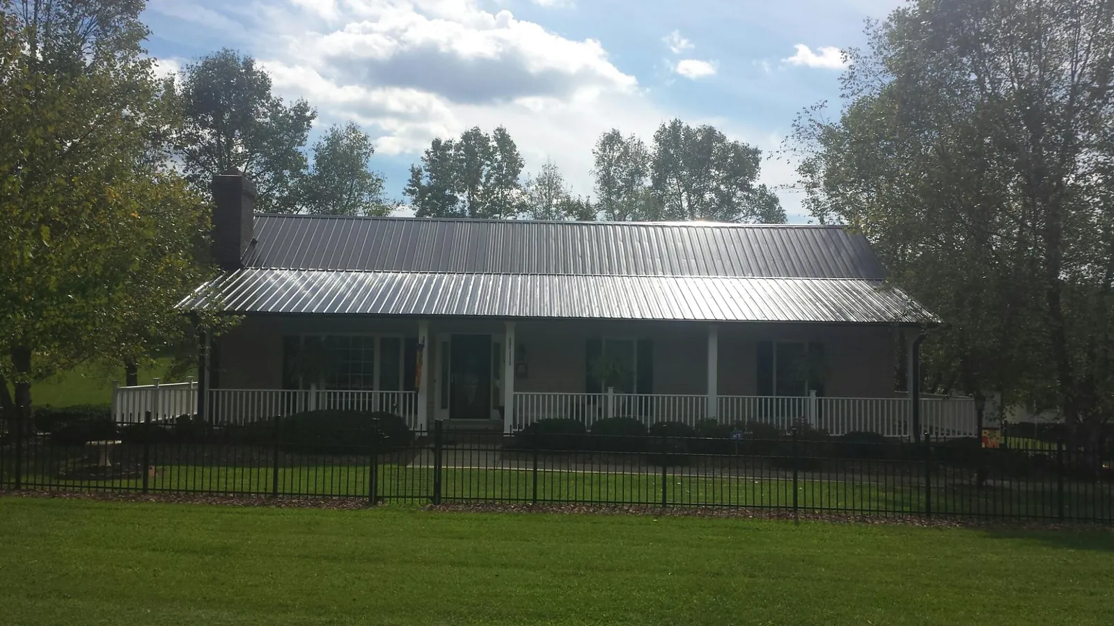 Gray metal roof on a brick ranch with a full width front porch — Gutter Guard Installation work by our crew in Deming