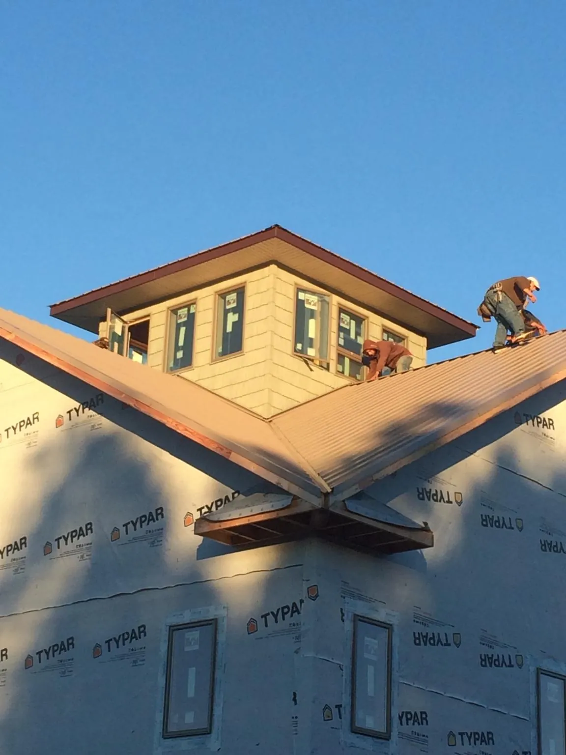 Roofers working around a rooftop cupola on a new metal roof at sunset — Roof Waterproofing in Deming by Roofing Brothers